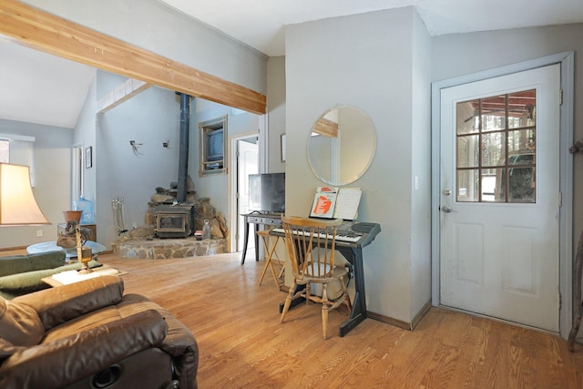 entrance foyer with lofted ceiling, light hardwood / wood-style floors, and a wood stove