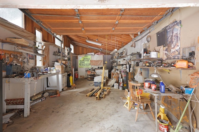 miscellaneous room with a workshop area, concrete flooring, and vaulted ceiling