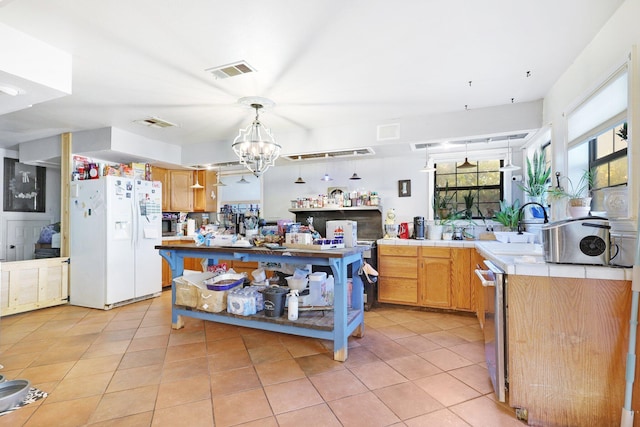 kitchen with dishwasher, white refrigerator with ice dispenser, light tile patterned floors, decorative light fixtures, and a chandelier