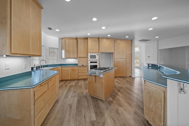 kitchen with sink, a center island, light brown cabinets, light hardwood / wood-style flooring, and stainless steel gas stovetop