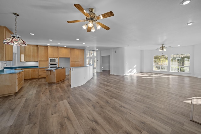 kitchen with white appliances, ceiling fan, decorative light fixtures, a center island, and light hardwood / wood-style floors