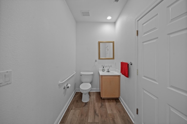 bathroom featuring wood-type flooring, vanity, and toilet