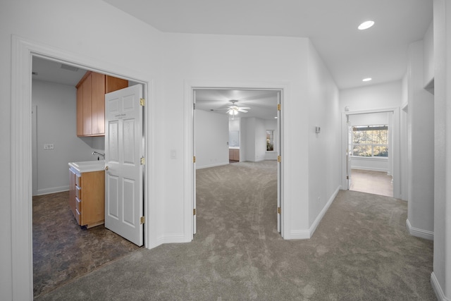 hallway featuring sink and dark colored carpet