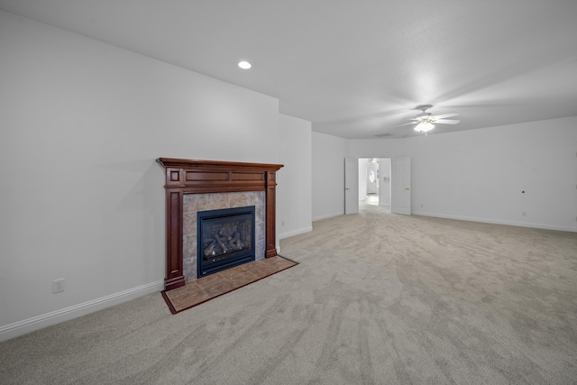 unfurnished living room featuring ceiling fan, light colored carpet, and a tile fireplace