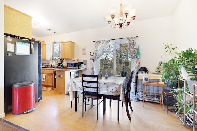 dining area with light hardwood / wood-style floors and a notable chandelier