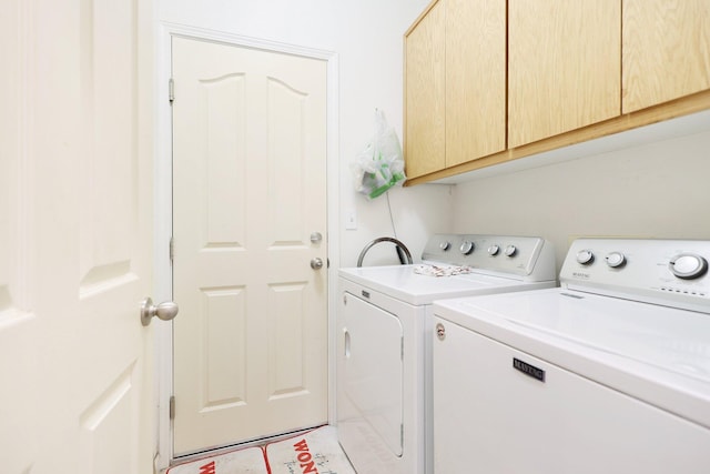 clothes washing area featuring washer and dryer and cabinets