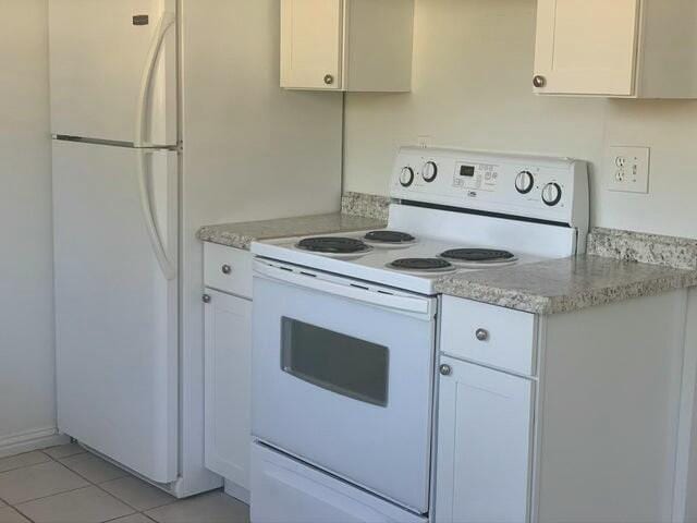 kitchen featuring light tile patterned floors, white appliances, white cabinetry, and light stone counters