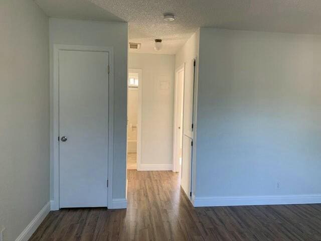 interior space featuring a textured ceiling and dark wood-type flooring