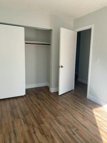 unfurnished bedroom with dark wood-type flooring and a closet