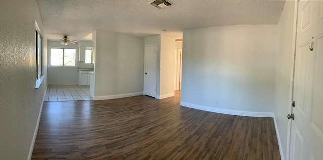 spare room featuring a textured ceiling, ceiling fan, and dark wood-type flooring