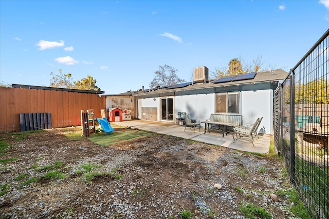 rear view of property featuring a patio and solar panels