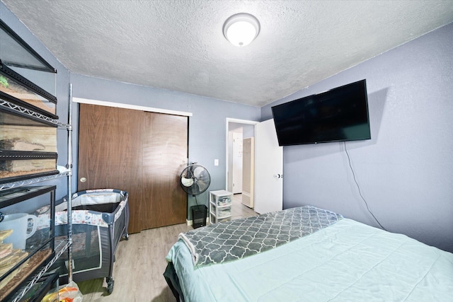 bedroom featuring light hardwood / wood-style floors and a textured ceiling