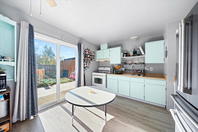 kitchen featuring white range with gas cooktop, sink, light hardwood / wood-style floors, and high end fridge