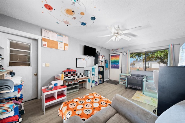 living room with a textured ceiling, light hardwood / wood-style flooring, and ceiling fan