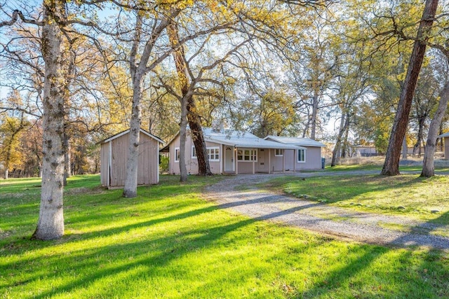 ranch-style house featuring a storage shed and a front lawn