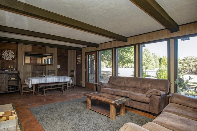 living room with beamed ceiling, a textured ceiling, and wooden walls