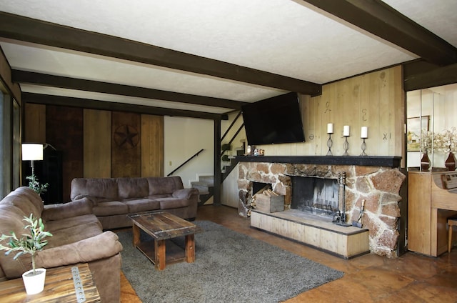 living room with beamed ceiling, a stone fireplace, and wood walls