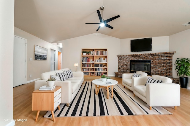 living room featuring ceiling fan, light hardwood / wood-style floors, a fireplace, and vaulted ceiling