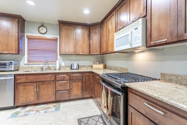 kitchen featuring light tile patterned flooring, light stone countertops, sink, and appliances with stainless steel finishes