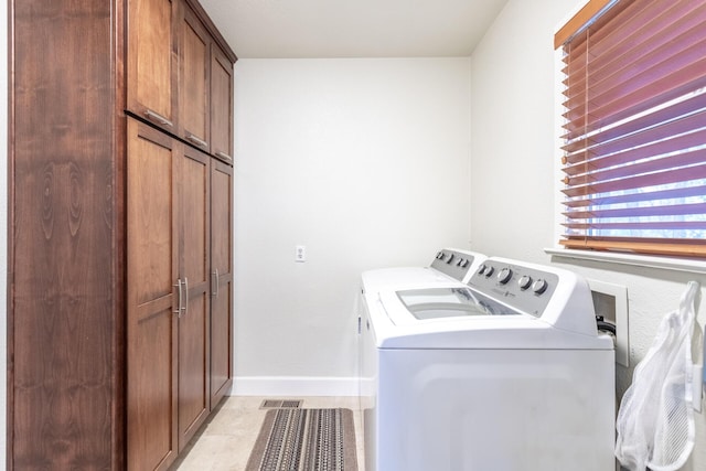 laundry room featuring cabinets, independent washer and dryer, and light tile patterned floors