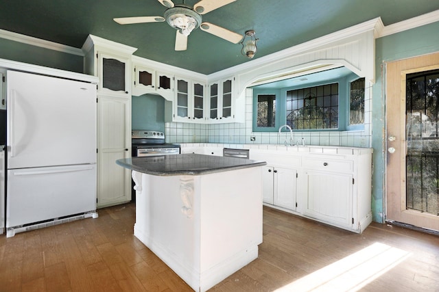 kitchen with crown molding, appliances with stainless steel finishes, white cabinets, a kitchen island, and decorative backsplash