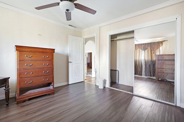 unfurnished bedroom with crown molding, a closet, ceiling fan, and dark hardwood / wood-style flooring