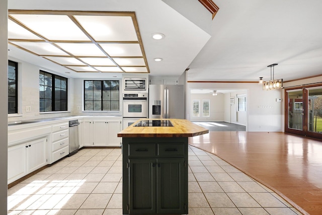 kitchen featuring butcher block counters, a center island, light tile patterned flooring, stainless steel fridge, and white cabinets