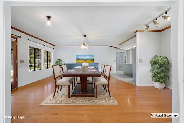 dining space with crown molding, rail lighting, and light hardwood / wood-style floors