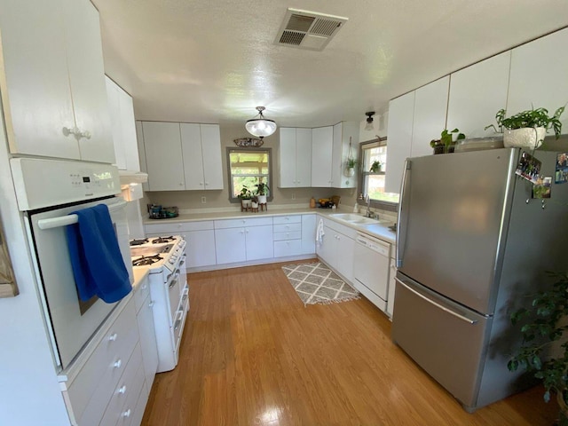 kitchen featuring sink, white appliances, light hardwood / wood-style flooring, a textured ceiling, and white cabinets