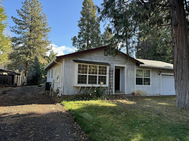 view of front of house featuring a garage, a front lawn, and central air condition unit