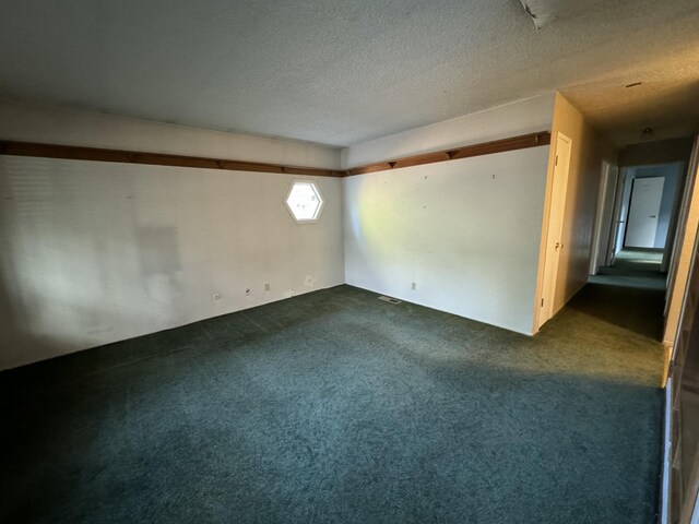 carpeted empty room with a textured ceiling