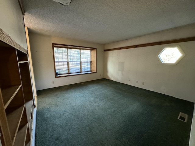 spare room featuring a textured ceiling and dark colored carpet