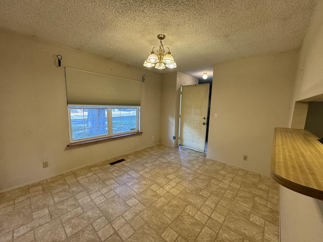 empty room with a chandelier and a textured ceiling