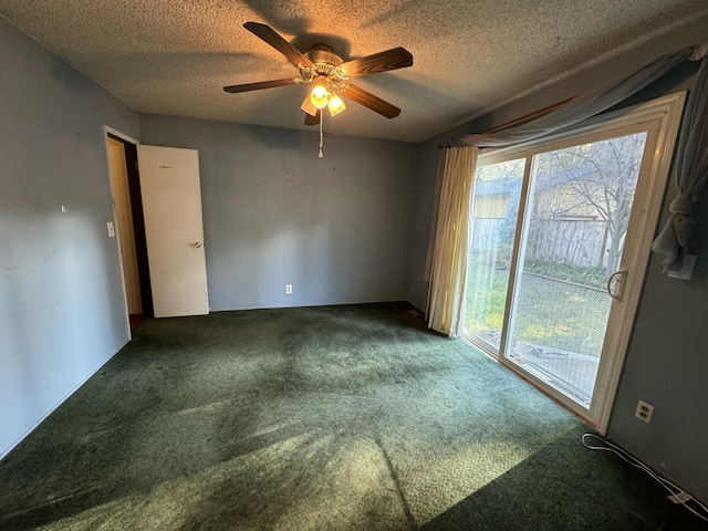 spare room featuring ceiling fan, dark carpet, and a textured ceiling