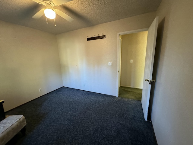 spare room with dark colored carpet, a textured ceiling, and ceiling fan