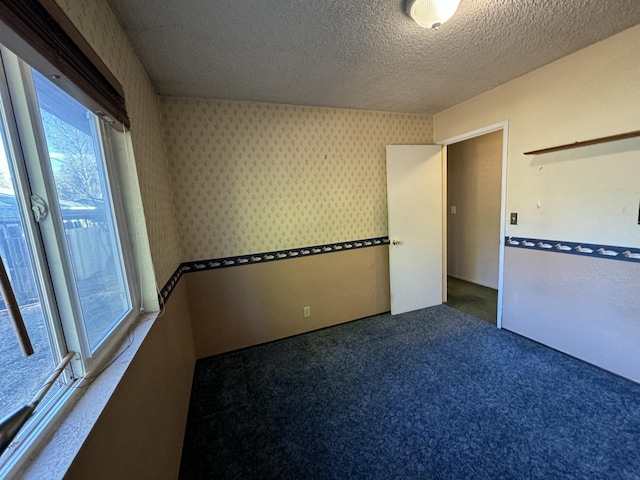 empty room with dark carpet and a textured ceiling