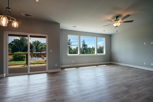 empty room featuring ceiling fan with notable chandelier and wood-type flooring