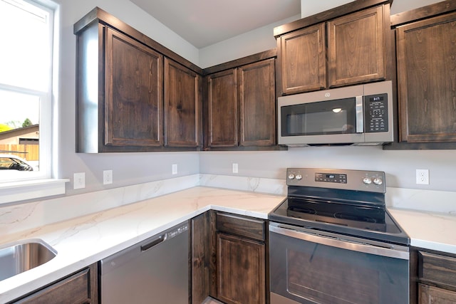 kitchen featuring dark brown cabinetry, light stone counters, sink, and stainless steel appliances