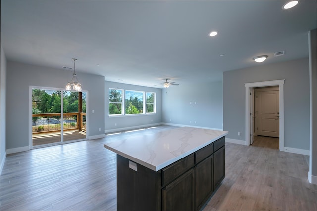 kitchen with dark brown cabinetry, ceiling fan, a center island, pendant lighting, and light hardwood / wood-style floors