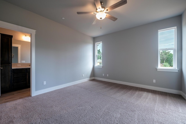 empty room with a wealth of natural light, ceiling fan, and light colored carpet