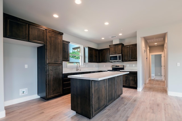 kitchen featuring dark brown cabinetry, a center island, stainless steel appliances, and sink