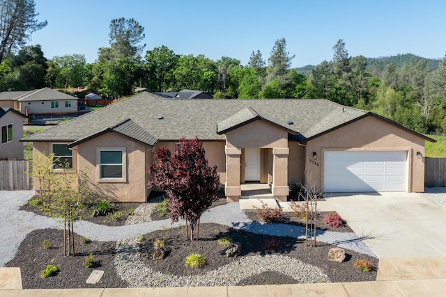 ranch-style home with roof with shingles, fence, and stucco siding