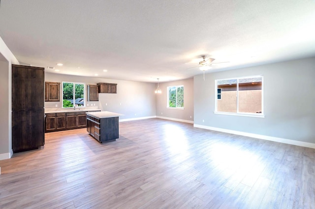 kitchen featuring dark brown cabinetry, a wealth of natural light, a center island, and light hardwood / wood-style floors