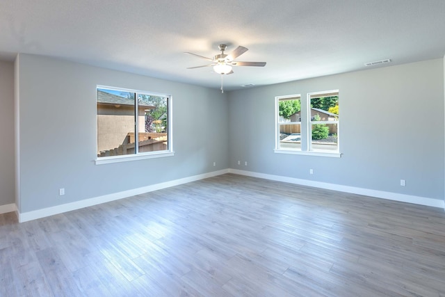 spare room featuring hardwood / wood-style floors, plenty of natural light, ceiling fan, and a textured ceiling