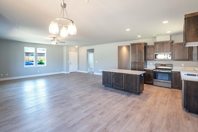 kitchen featuring pendant lighting, sink, a kitchen island, appliances with stainless steel finishes, and light hardwood / wood-style floors