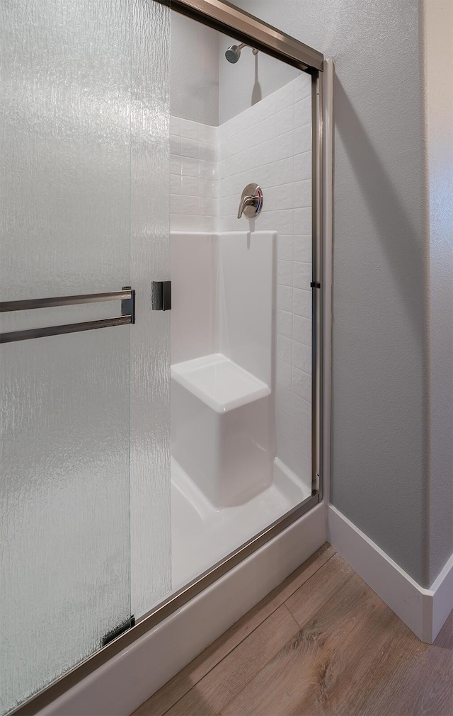 bathroom with wood-type flooring and a shower with shower door