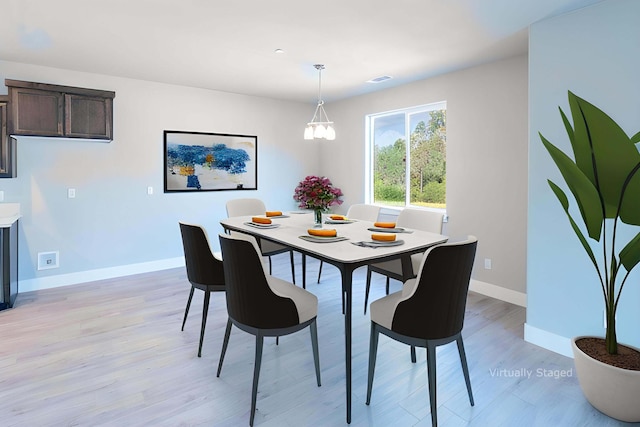 dining area with light hardwood / wood-style floors and an inviting chandelier