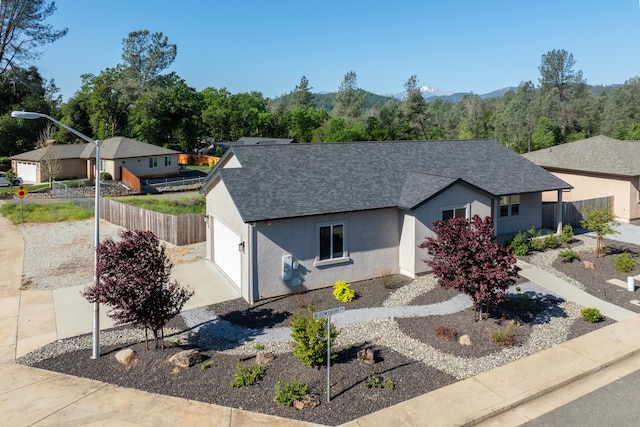 view of front of home with roof with shingles, stucco siding, fence, and driveway