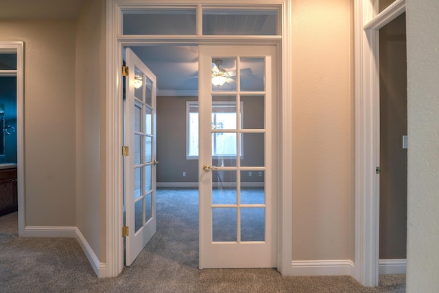 hall featuring french doors, crown molding, and dark carpet