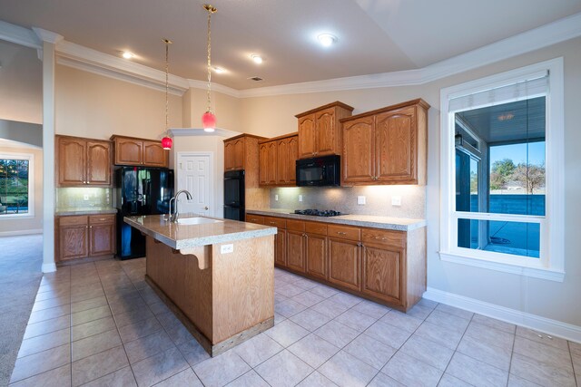 kitchen featuring sink, light tile patterned floors, a breakfast bar, a kitchen island with sink, and black appliances